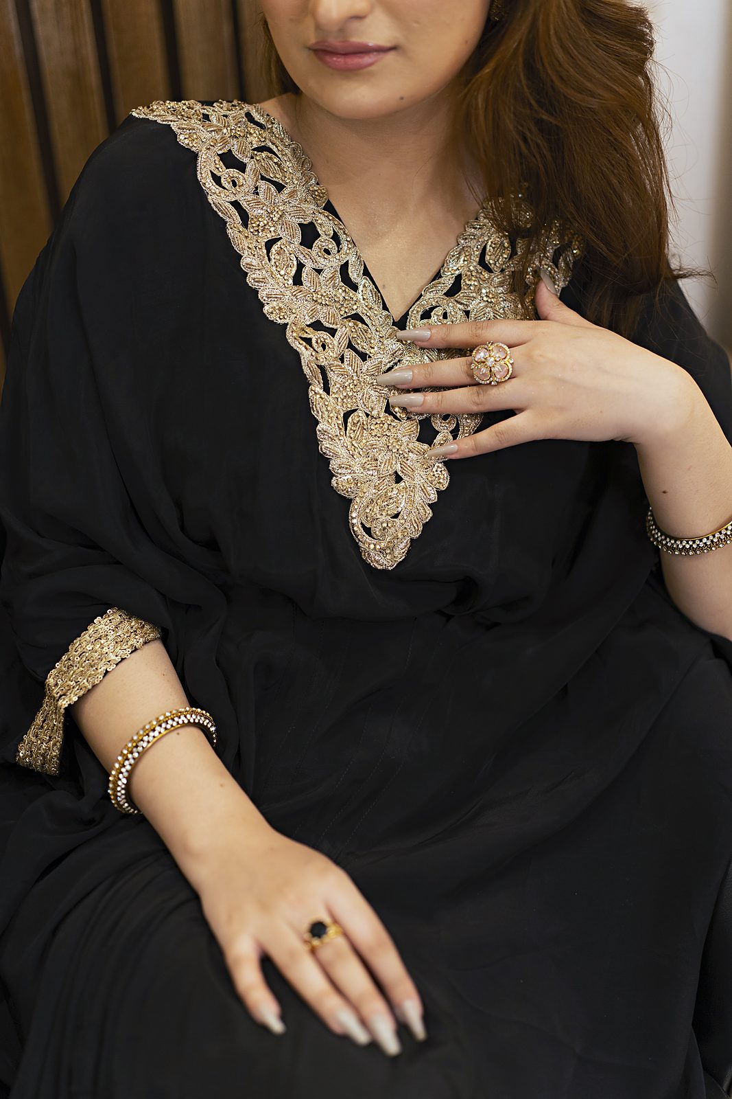 Close-up of the handmade gold lace V-neckline on a black Russian silk kaftan